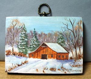 Old barn scene in snow painted on piece of board.