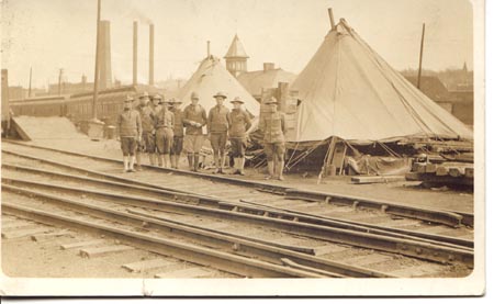 WWI postcard men in front of barracks/train