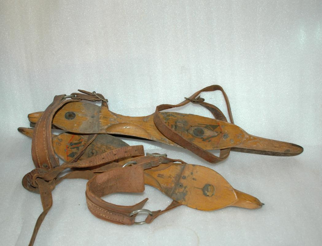 A pair of antique wooden ice skates from Amsterdam with leather straps.