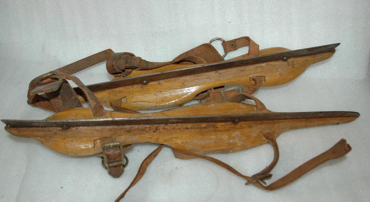 A pair of antique wooden ice skates from Amsterdam with leather straps.