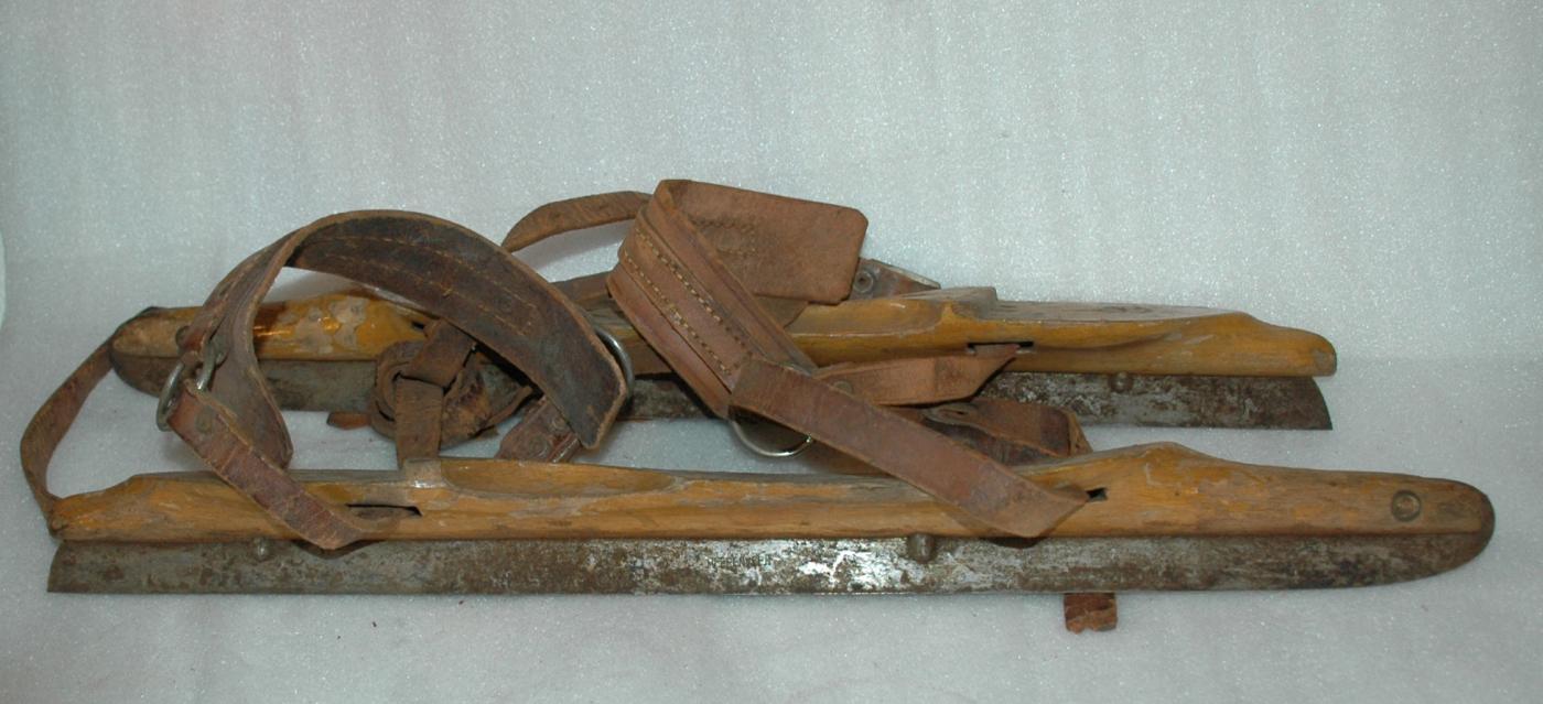 A pair of antique wooden ice skates from Amsterdam with leather straps.