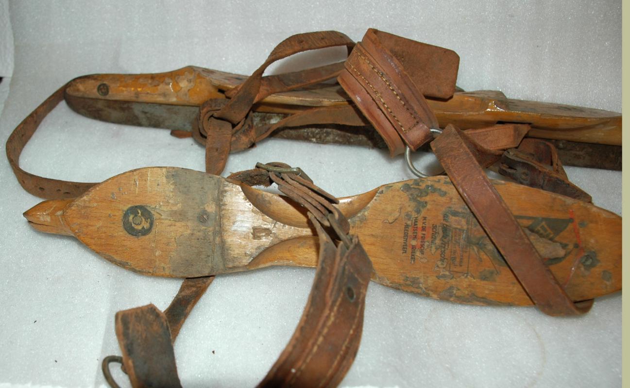 A pair of antique wooden ice skates from Amsterdam with leather straps.