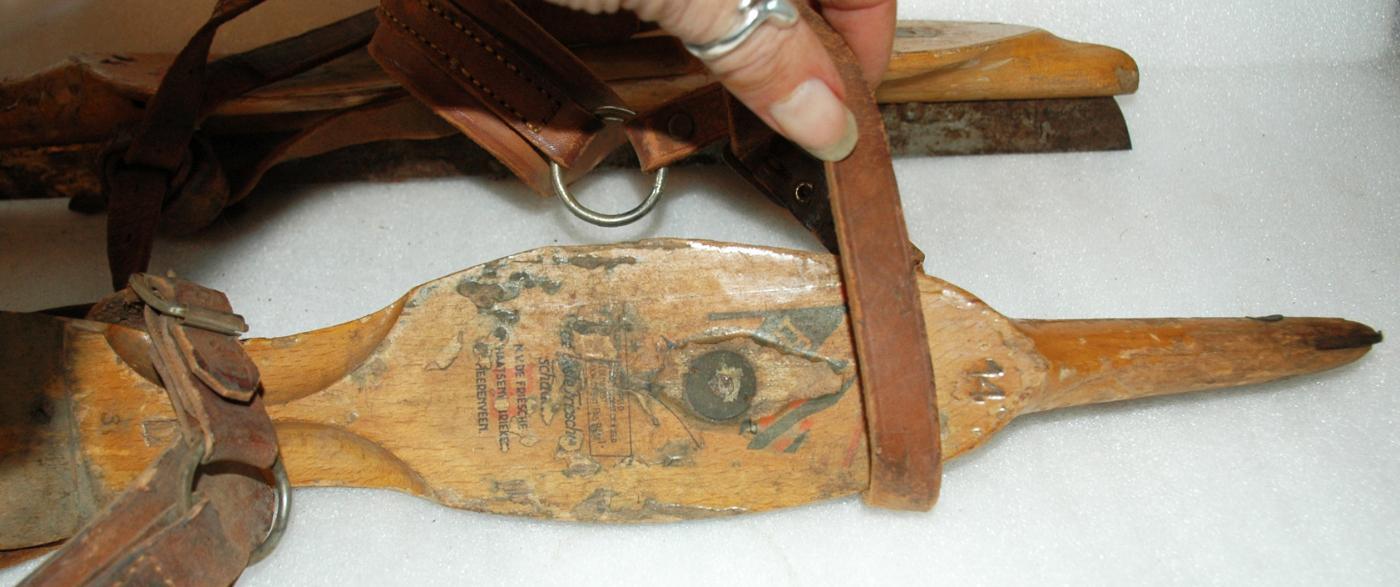 A pair of antique wooden ice skates from Amsterdam with leather straps.