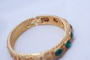 Lovely green glass stone/gold tone hinged bangle bracelet.